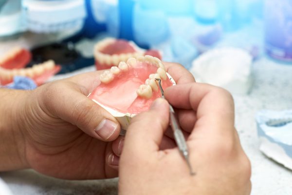 Dentist makes a dental implant prosthesis made of plaster cast. Model of the human jaw.